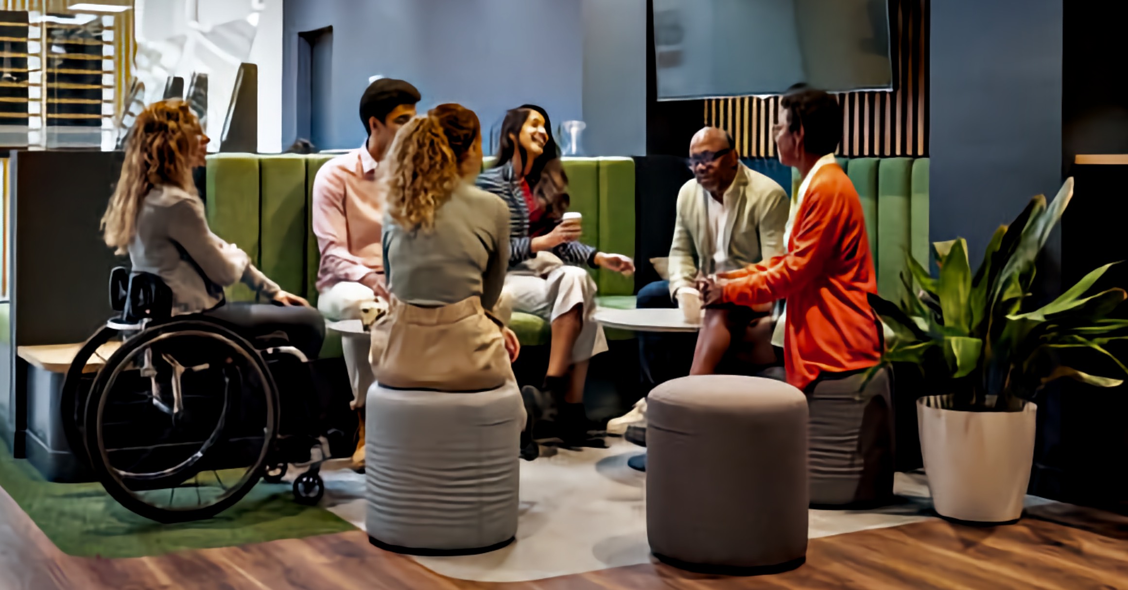 A small diverse meeting with participants in a circle, including a woman using a wheelchair, engaged in consultation