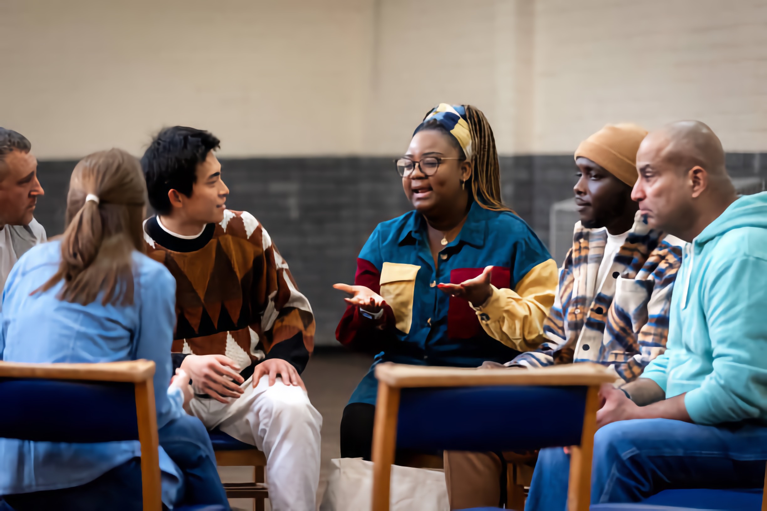 An animated black woman smiles as she leads a small mixed-race group discussion