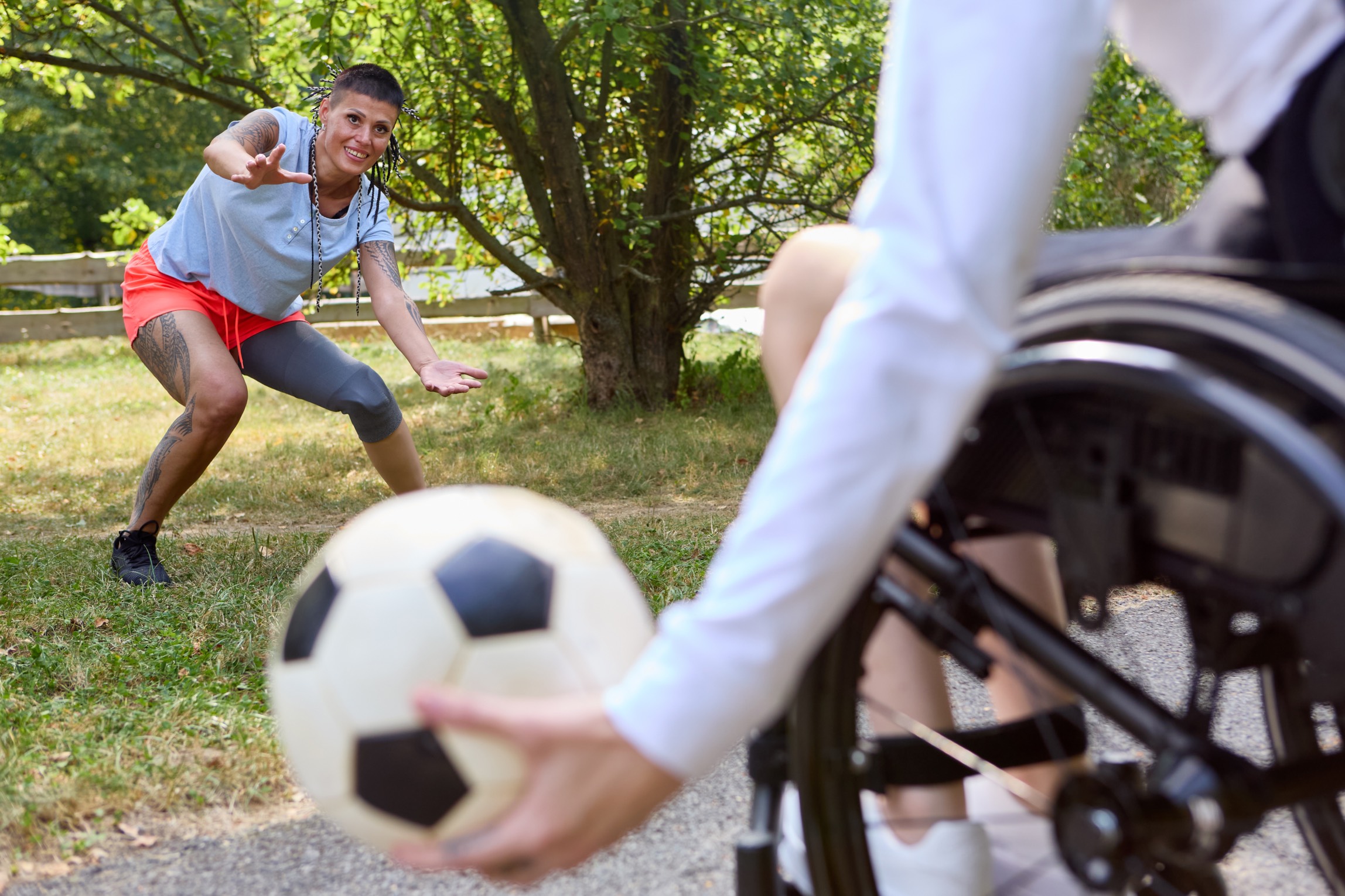 A person using a wheelchair and friends playing soccer outdoors, showcasing joy, inclusion, and adaptive sports