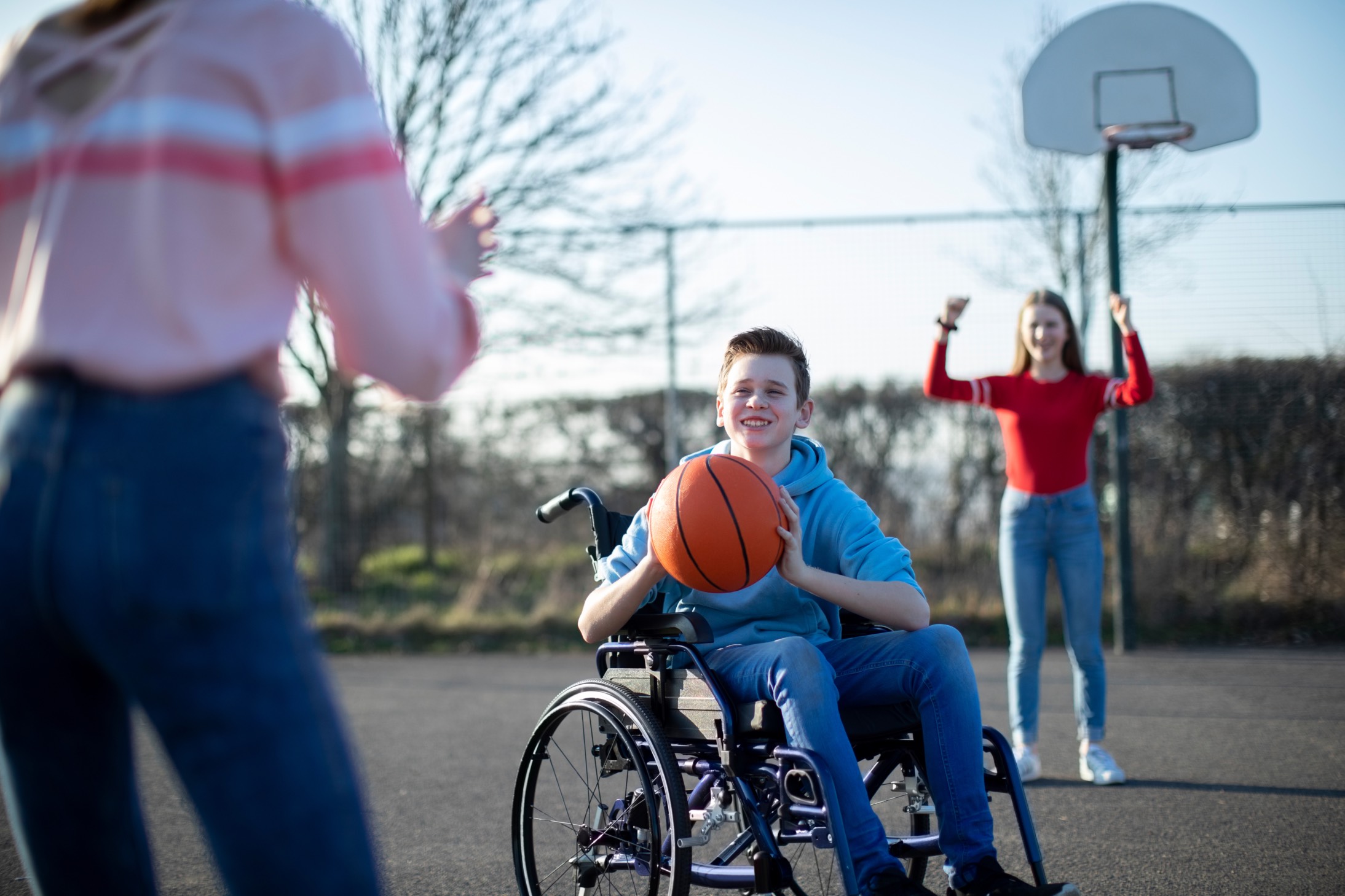 Teenage Boy using a Wheelchair Playing Basketball With Friends