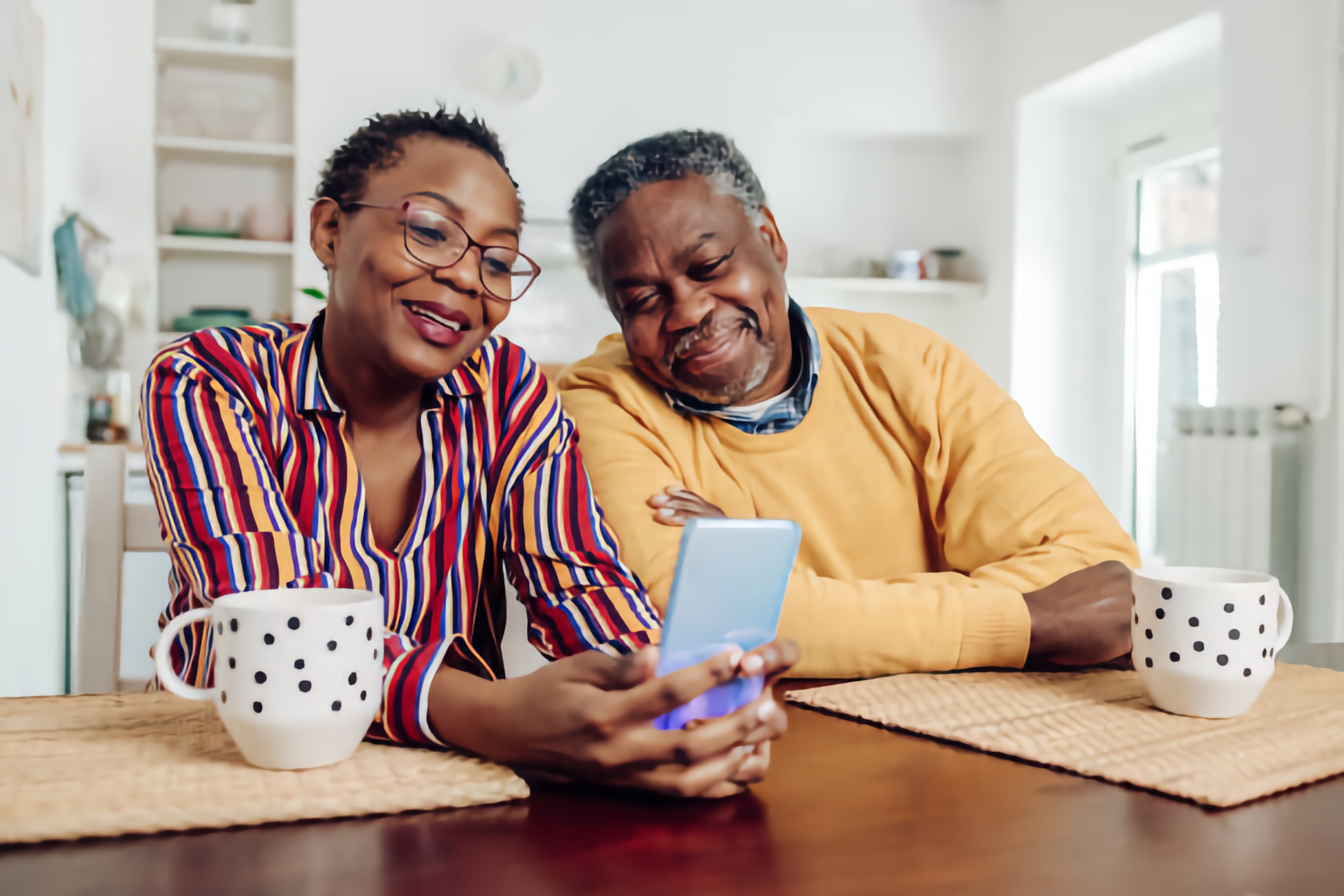 An older Black couple looking at information together on a smartphone.