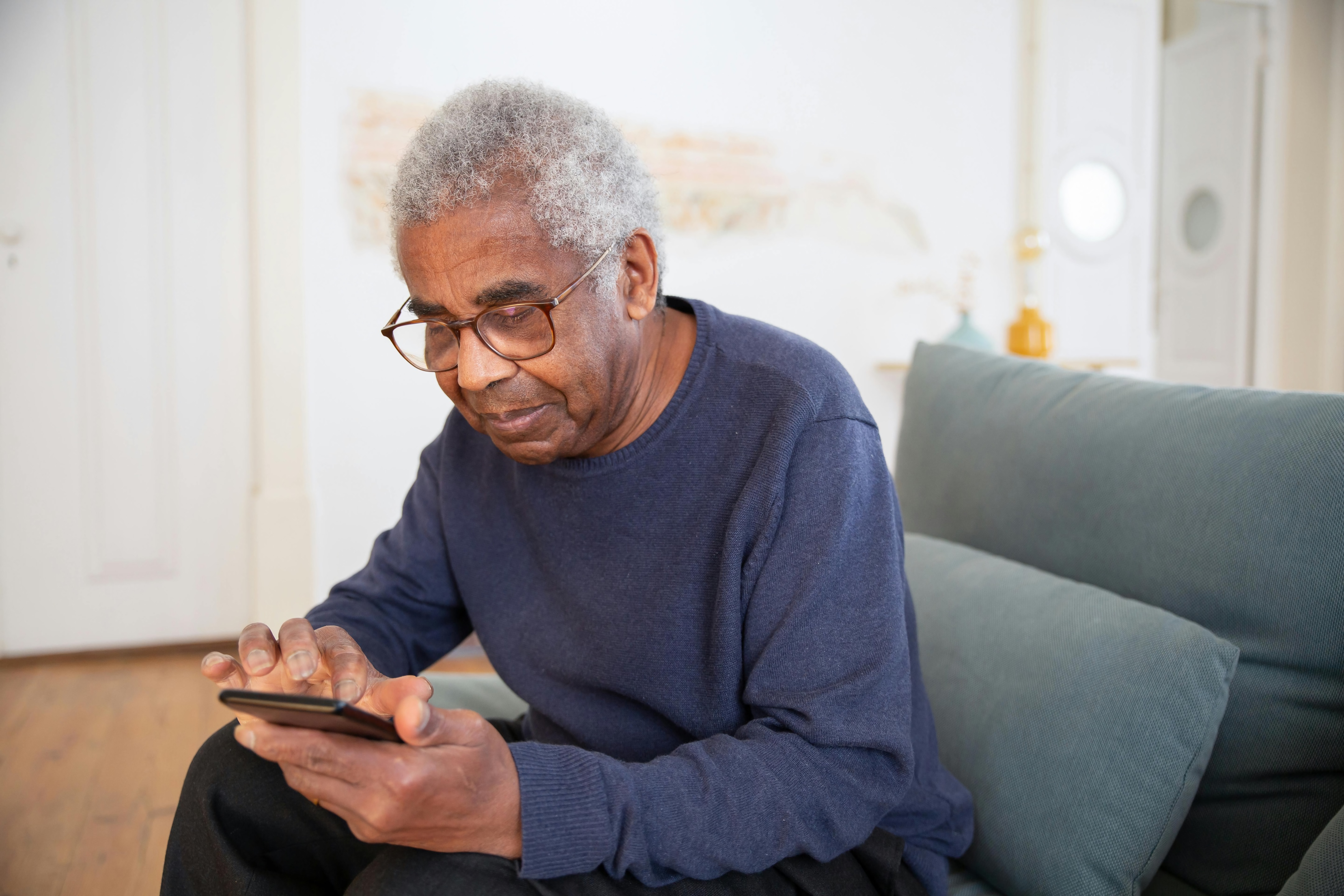 An older Black man accesses information on his smartphone.