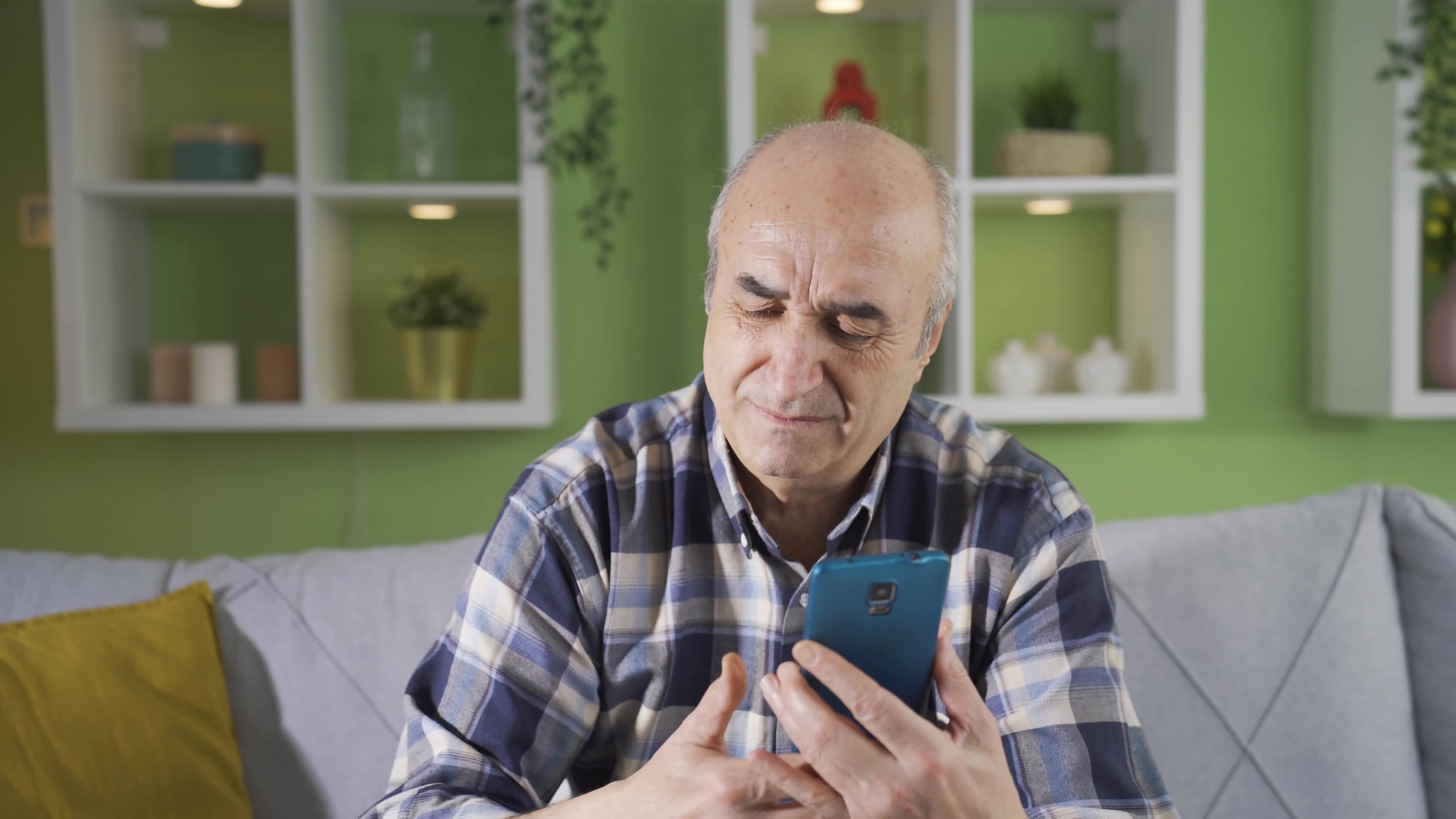 An older man accesses information on his phone in his living room.