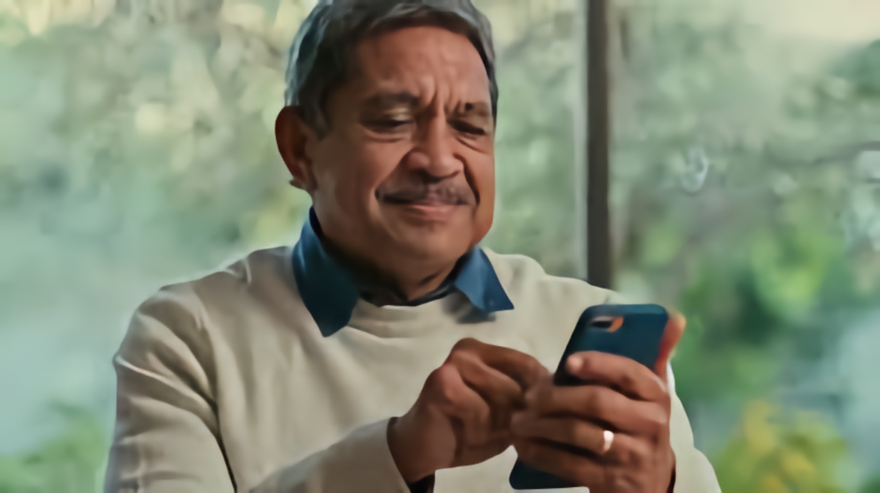 An older Latino man accesses information on his phone.j