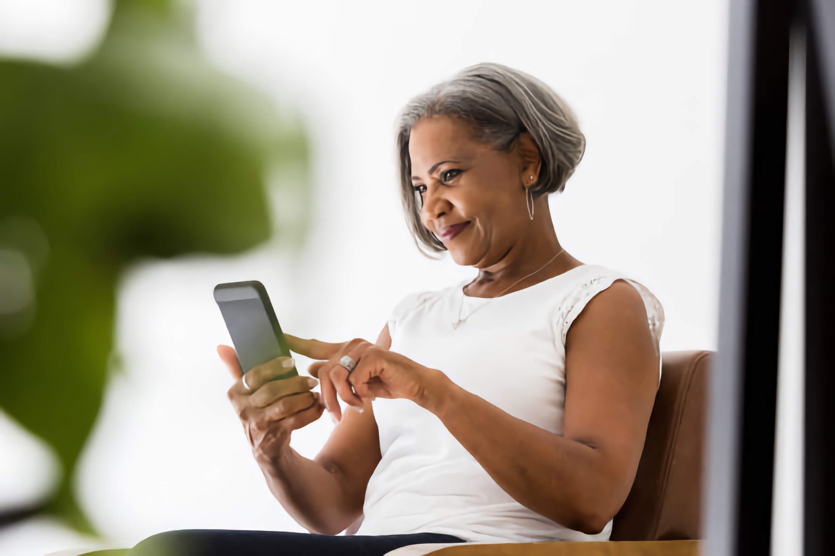 An older mixed-race woman accesses information on her phone.