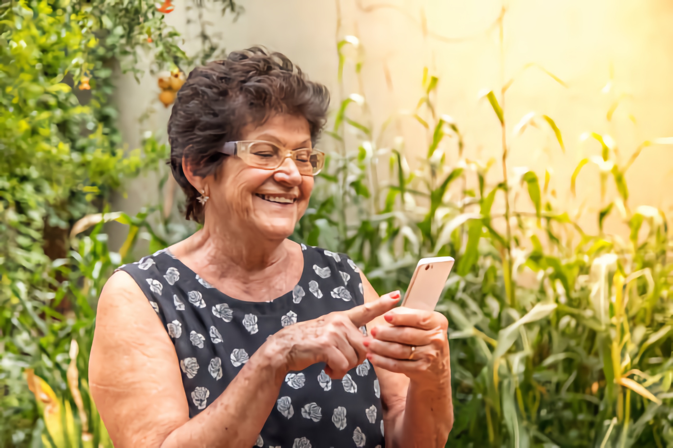 An older woman out in a garden accesses information on her smartphone.