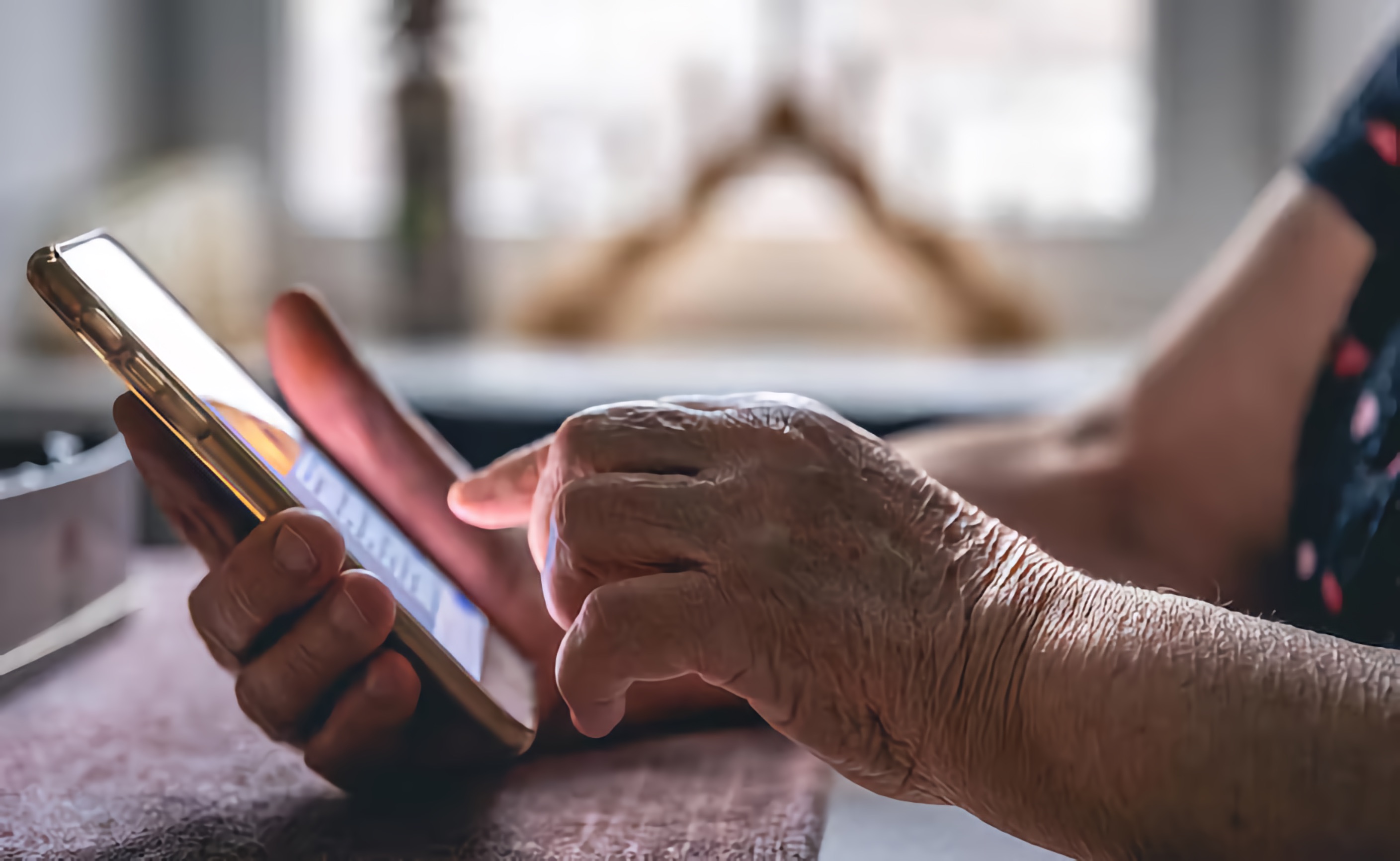 Close up of an older woman's hands using her phone to access information.