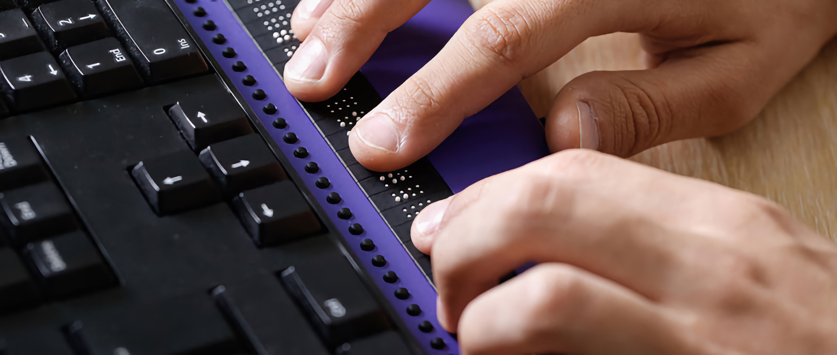 Close-up of hands reading a refreshable Braille display.