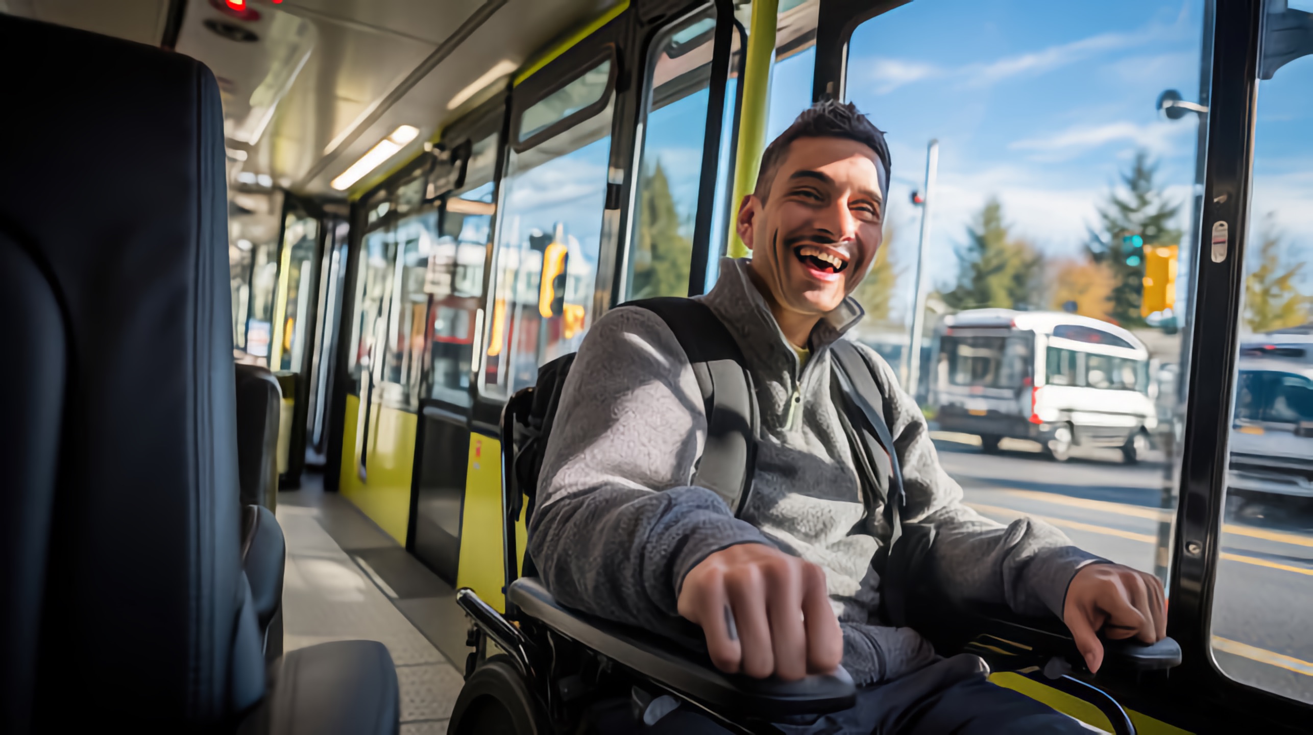 Man using a motorized wheel chair smiles while riding the bus.