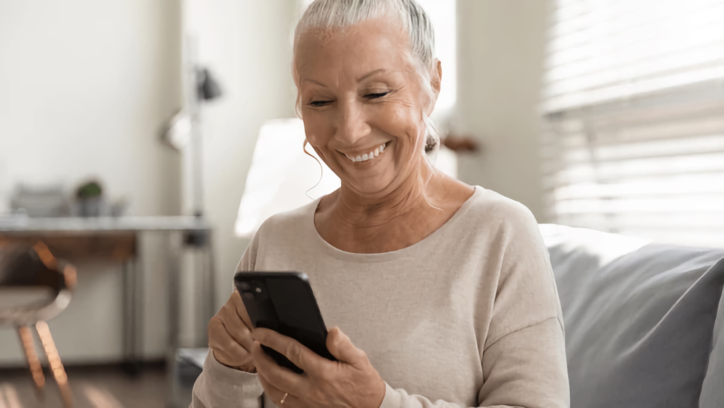 Older woman smiles as she accesses information on her phone.