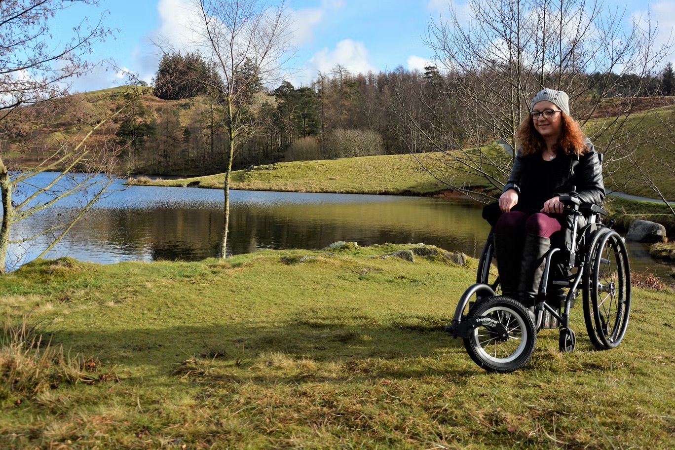 Carrie-Ann Lightly, adult woman using a wheelchair with a power add-on, outdoors in the Lake District;
