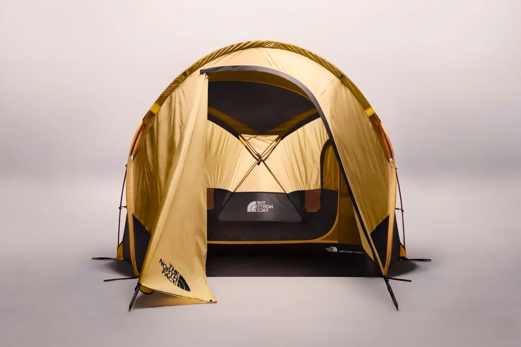 Color photo of a yellow and black North Face Universal dome tent with its front entry flap open, set against a plain gray studio background.