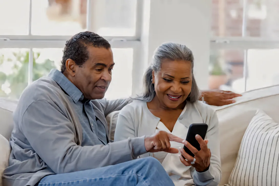 An older Latino couple look at information on a smartphone together.j